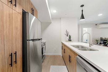 A modern kitchen with a stainless steel refrigerator and wooden cabinets.